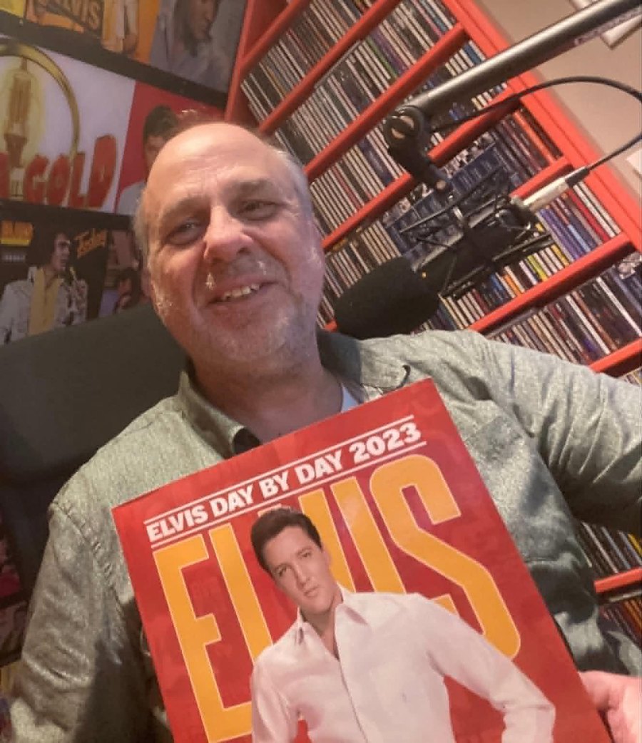 Fred van Veen in zijn studio, met een Elvis-jaarboek in zijn handen